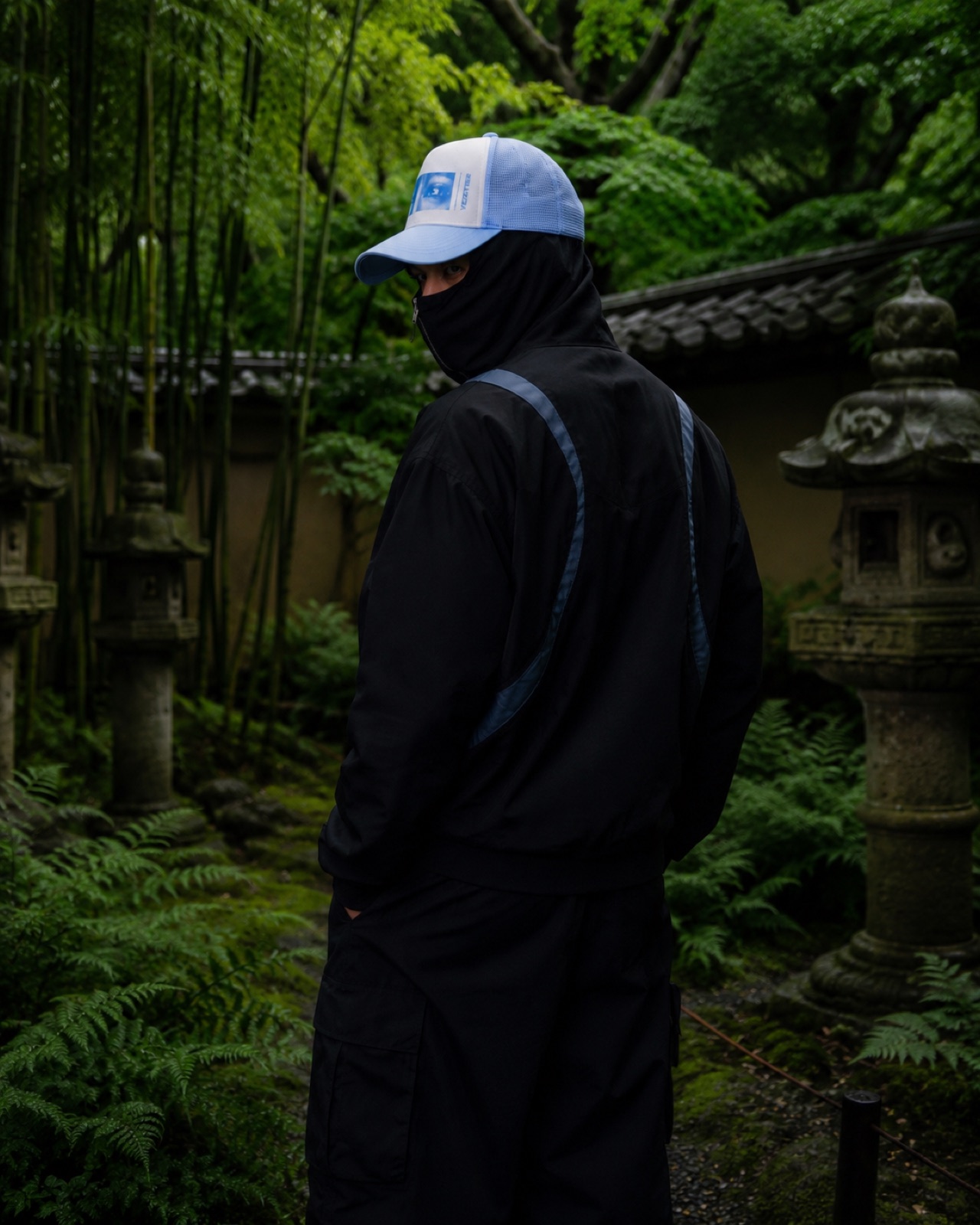 Back view of the black palm track jacket in the garden