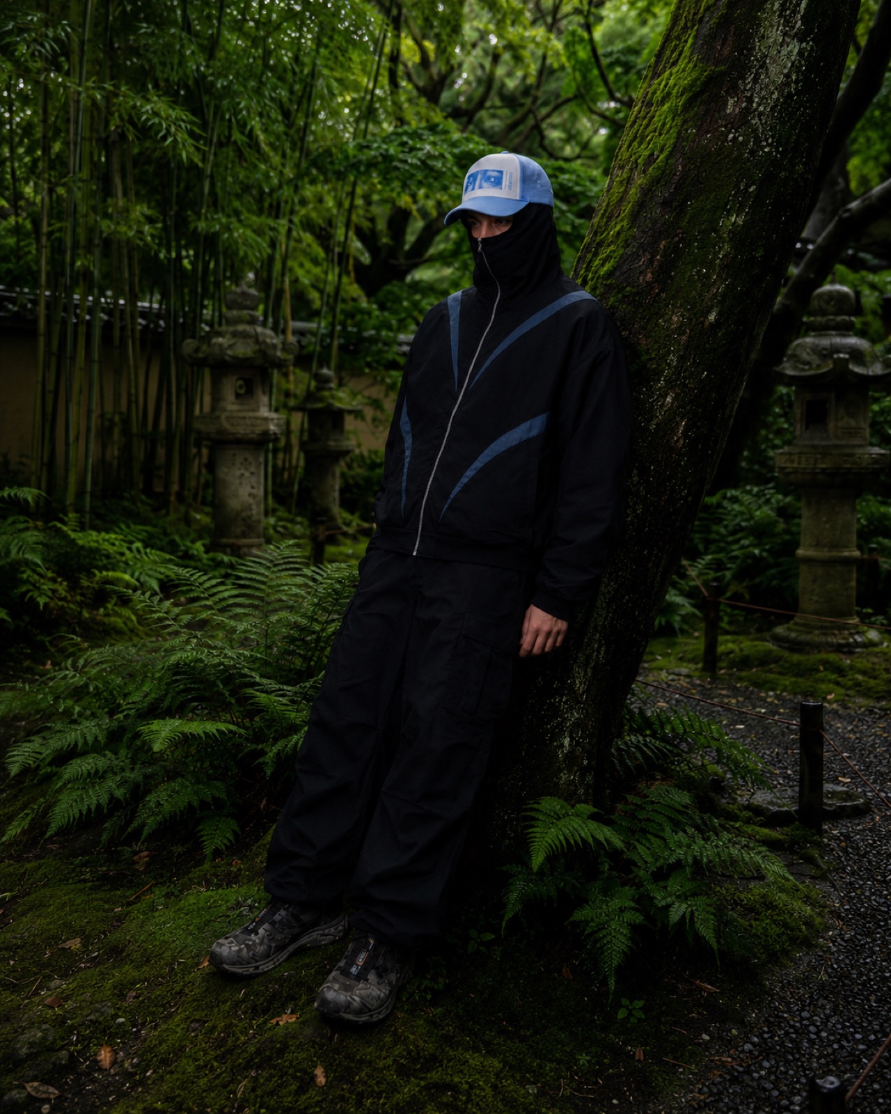 Model in the track jacket beside a moss-covered tree
